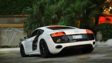 Белый Audi R8 подъезжает к роскошному дому в сумерках